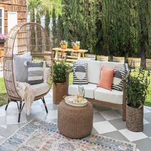 Inviting patio setup showcasing a wicker chair, ottoman, and a rug, designed for outdoor comfort and style.