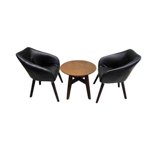 Two stylish black leather chairs with a table in between, offering a modern and inviting seating arrangement.